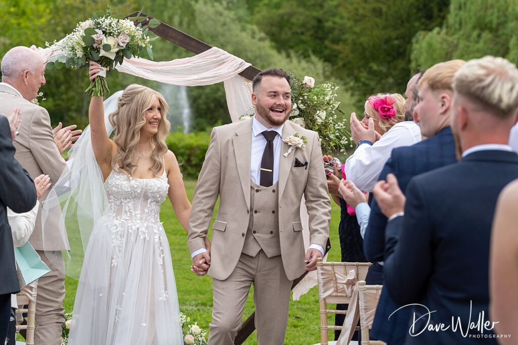 Bride and groom celebrating outdoors with guests.