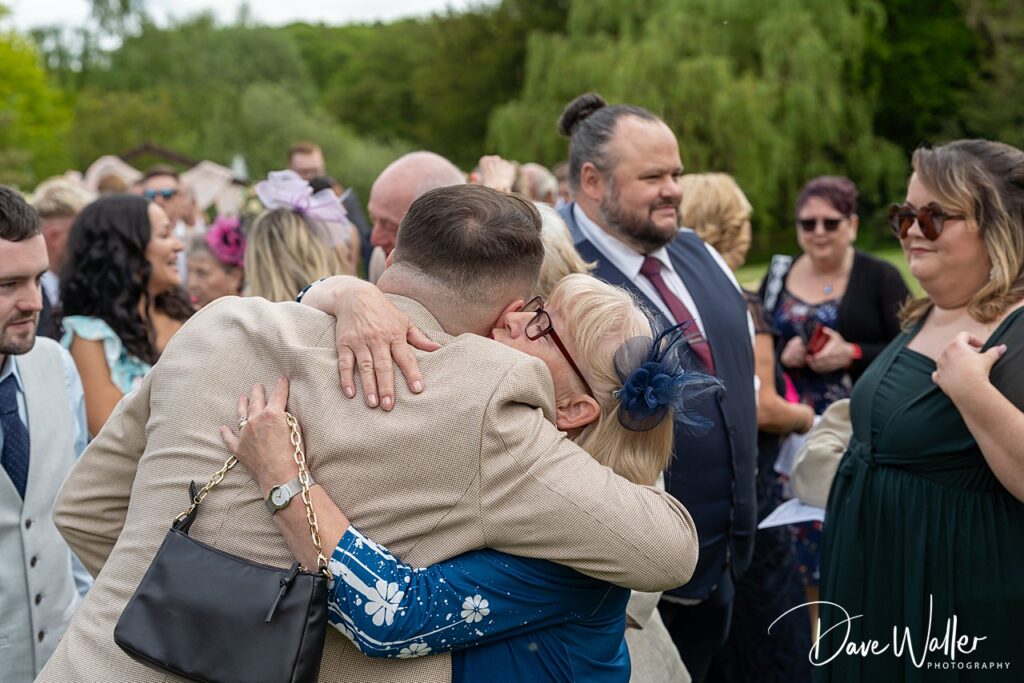 Guests hugging at outdoor wedding reception.