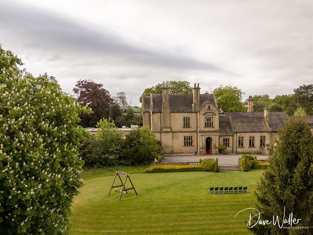 Historic manor house with lush garden and trees.