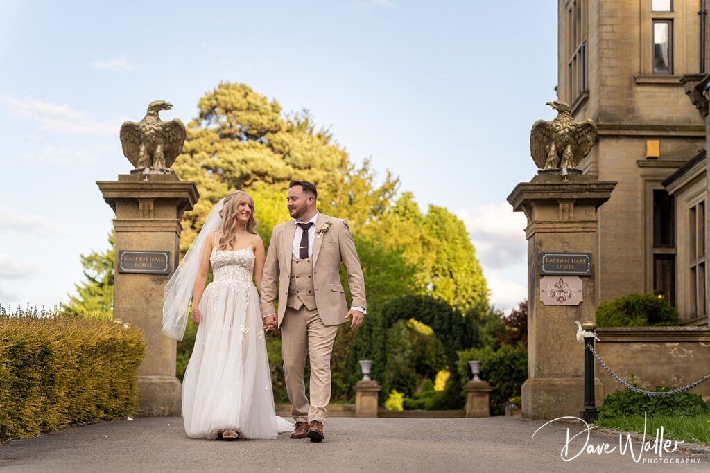 Bride and groom walk at Bagden Hall Hotel entrance.
