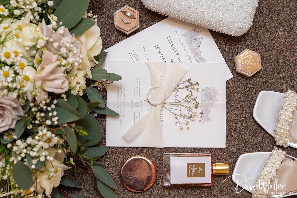 Wedding invitation with flowers, rings, and perfume.