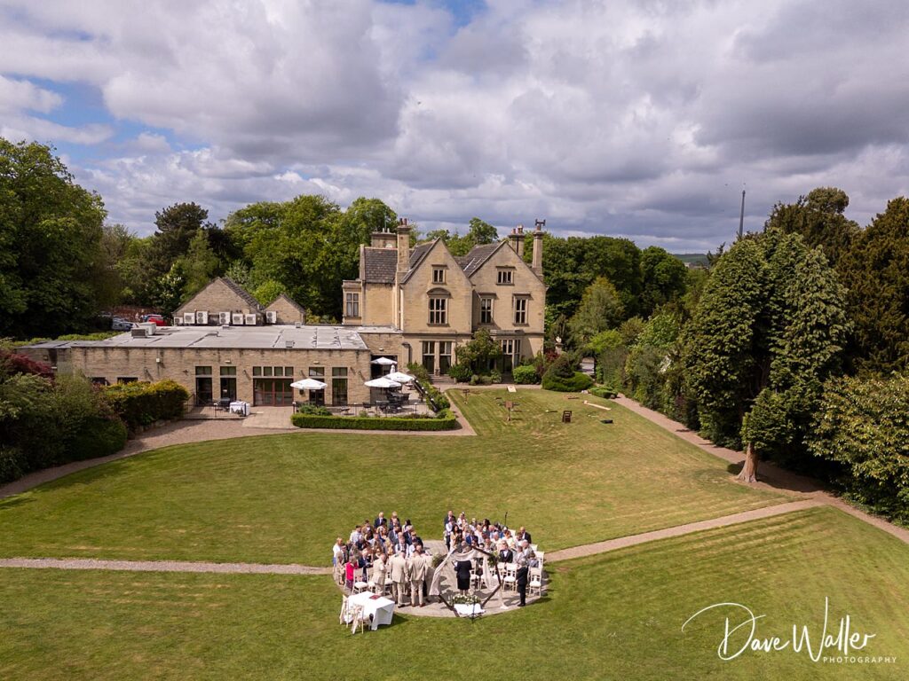 Aerial view of Manor House with wedding guests outside.