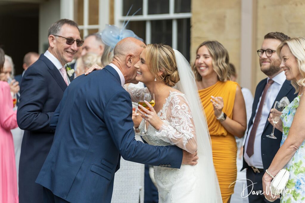 Bride greets guests at wedding reception outdoors.