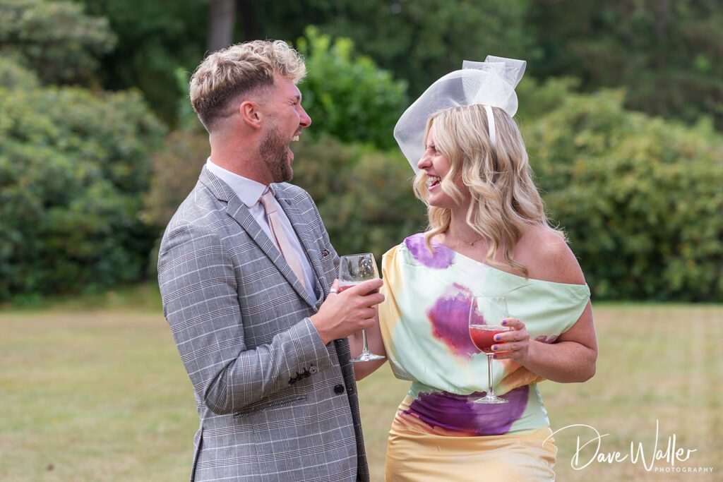 Smiling couple with drinks in garden party.