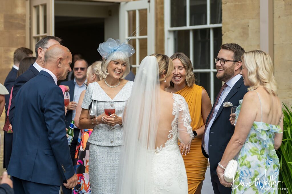 Smiling wedding guests conversing outside venue.