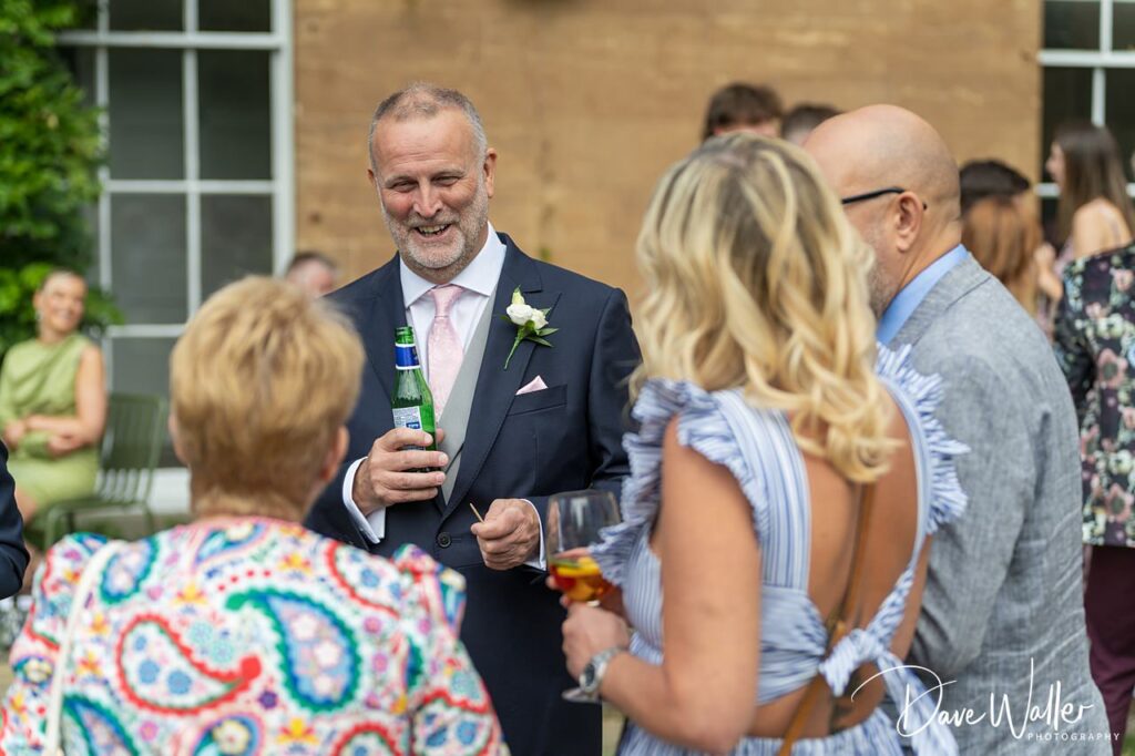 Smiling man in suit holding drink at social event.