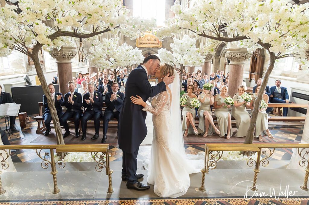 Bride and groom kiss in church ceremony.