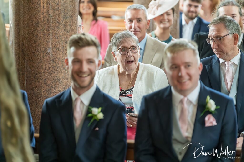 Wedding guests smiling and laughing at ceremony.