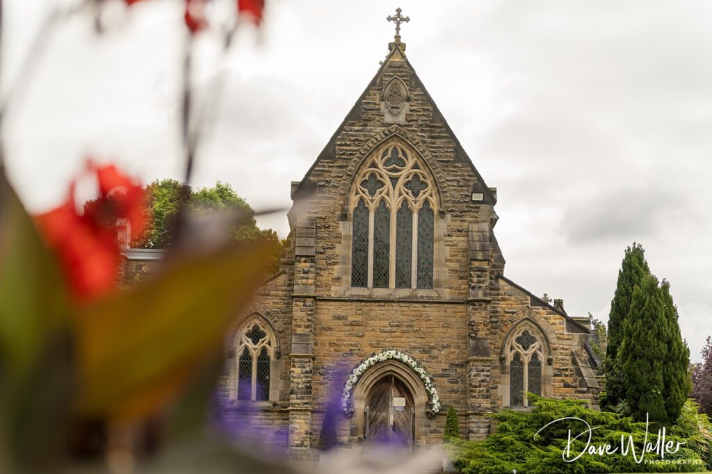 Gothic church facade with floral archway, trees foreground.