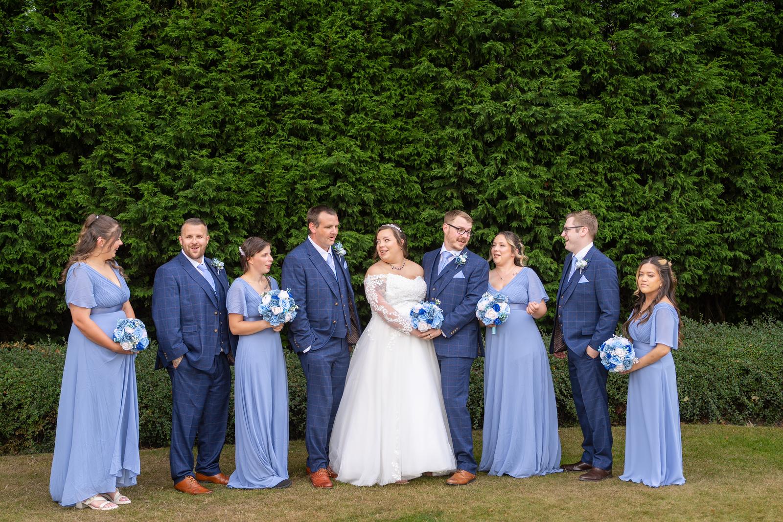 Shannon and Scott with their bridesmaids in blue and groomsmen in navy suits on the lawn