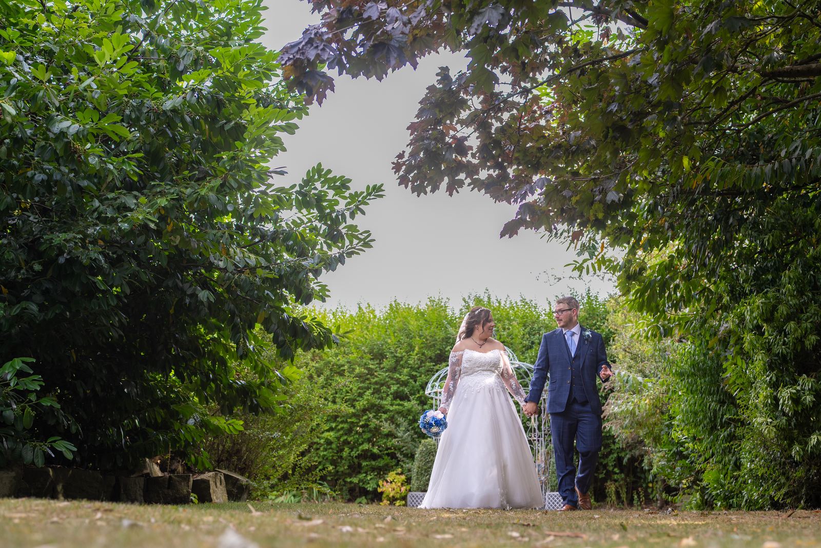 Shannon and Scott standing among the trees in the grounds of Holdsworth House