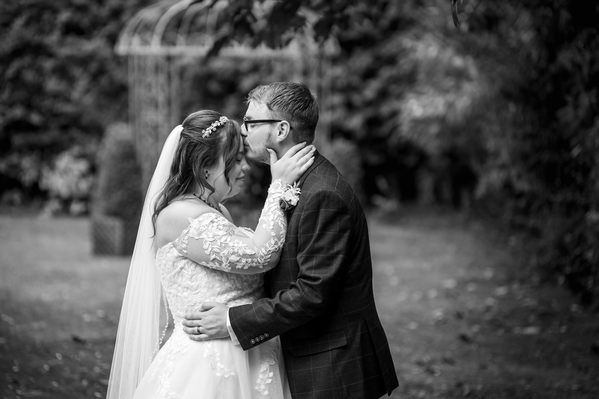 Black and white picture of Scott kissing Shannon on the forehead in the gardens