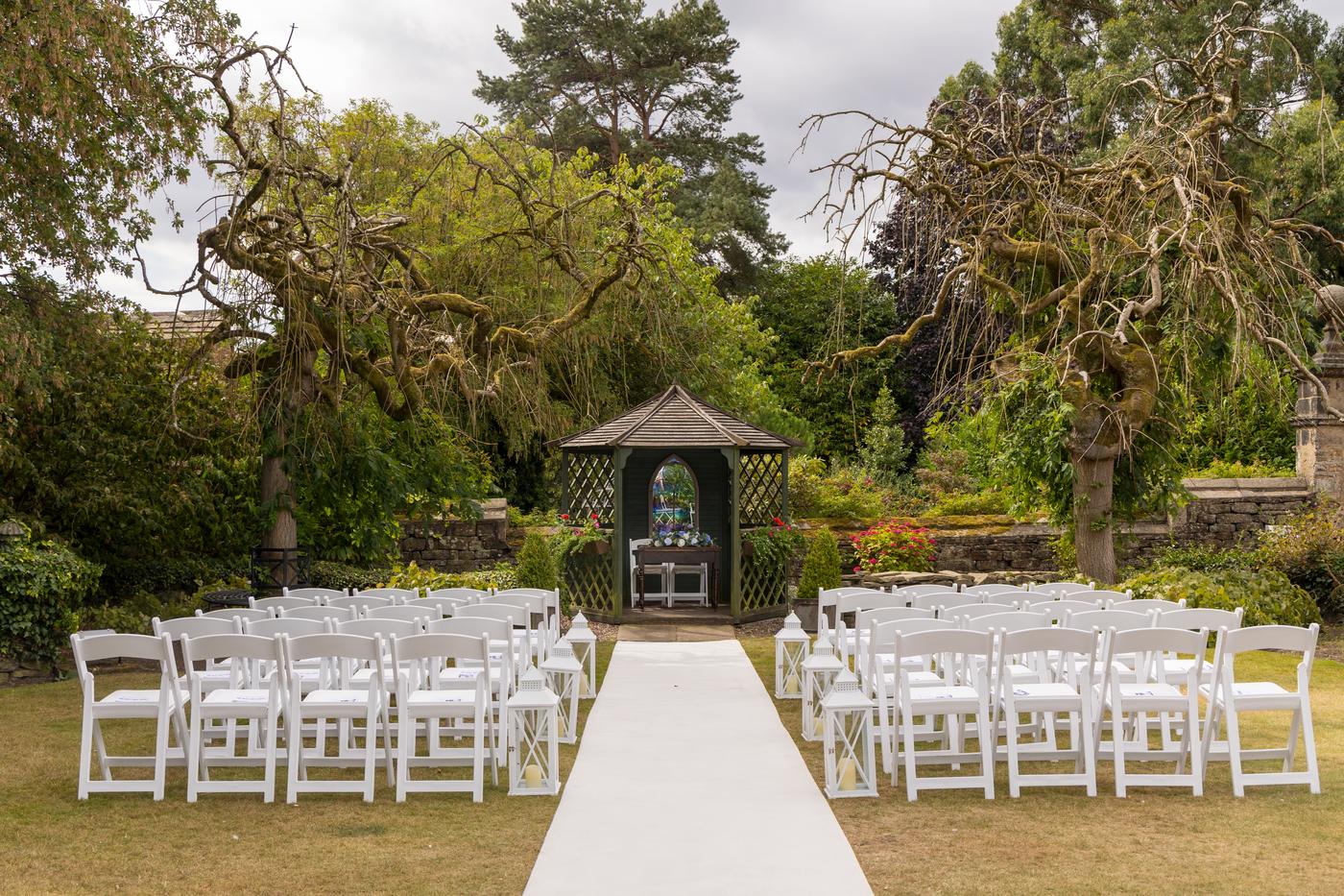 The garden ceremony set up with white chairs and an aisle leading to the gazebo at Holdsworth House