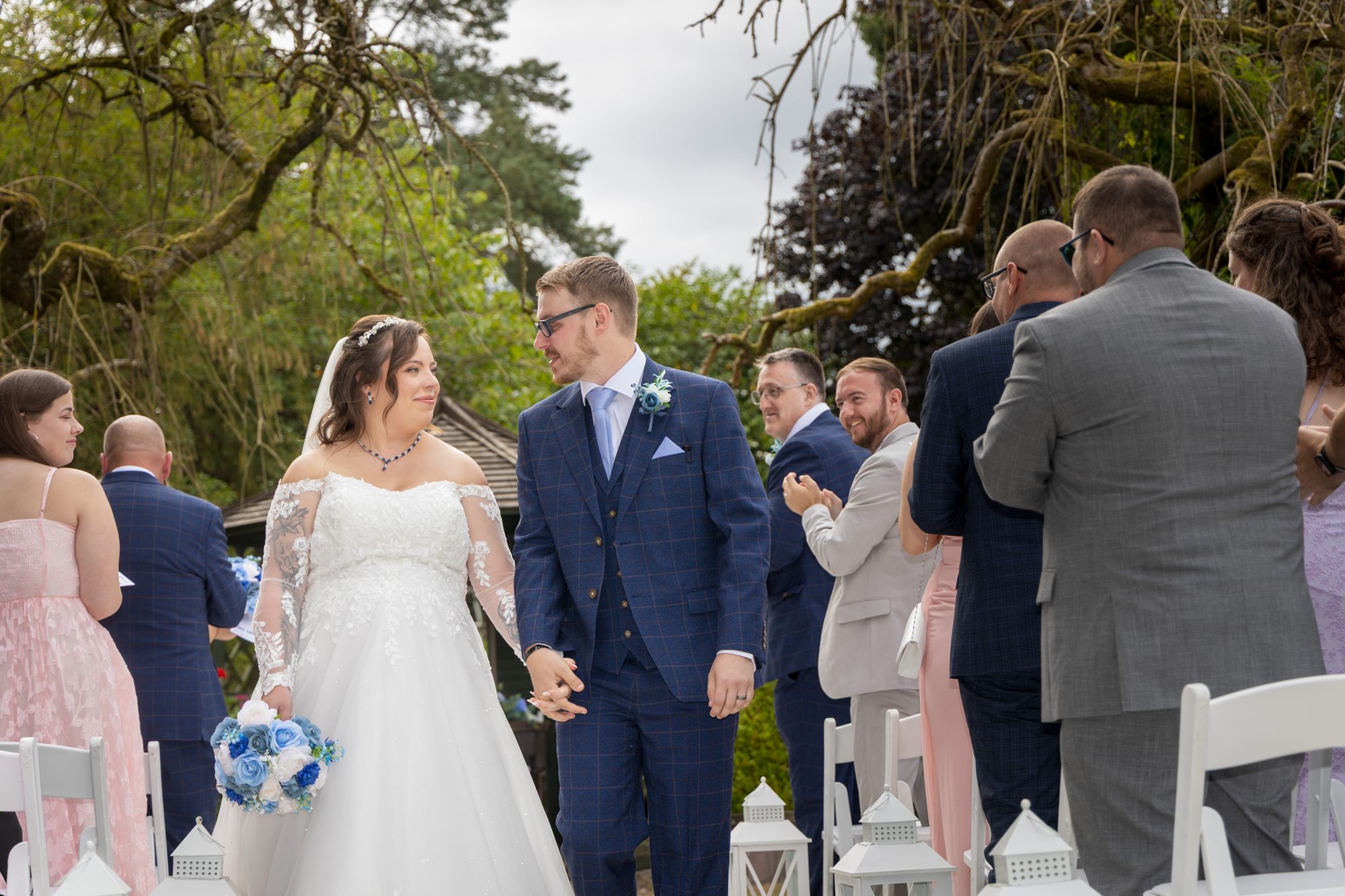 Shannon and Scott walking back up the aisle as newlyweds, smiling at their guests