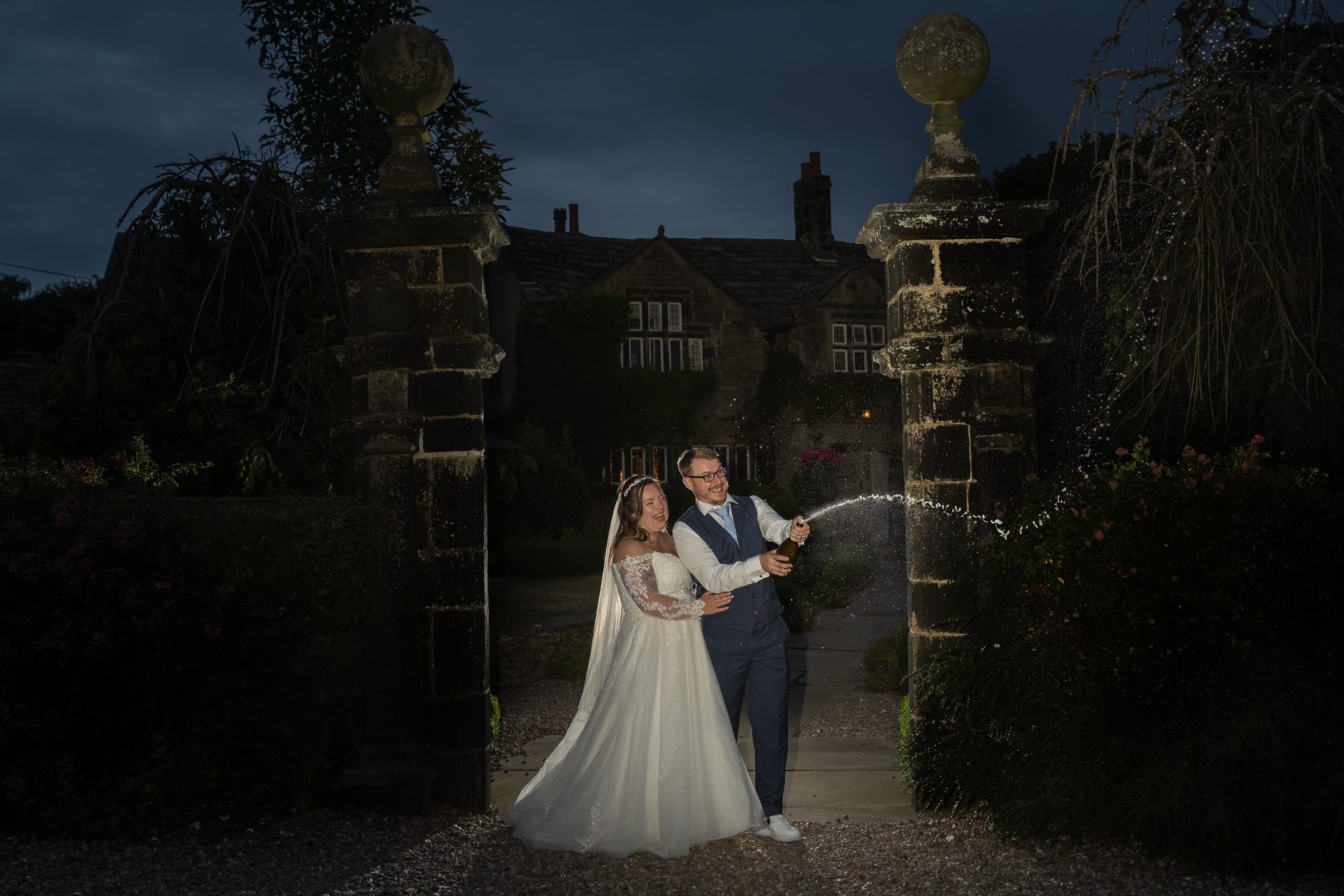 Twilight portrait of Shannon and Scott at the stone gateway of Holdsworth House