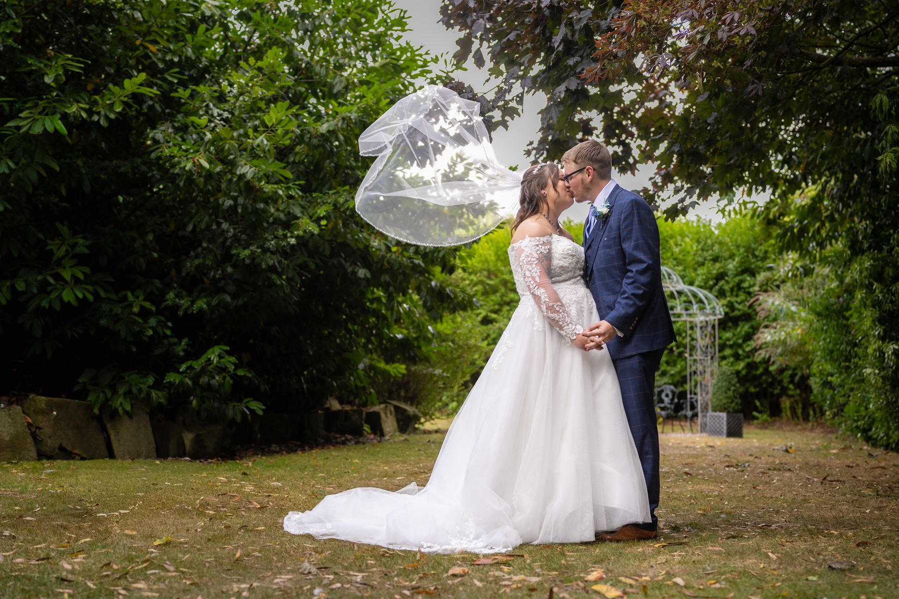 Shannon's veil catching the breeze as she and Scott kiss on the lawn
