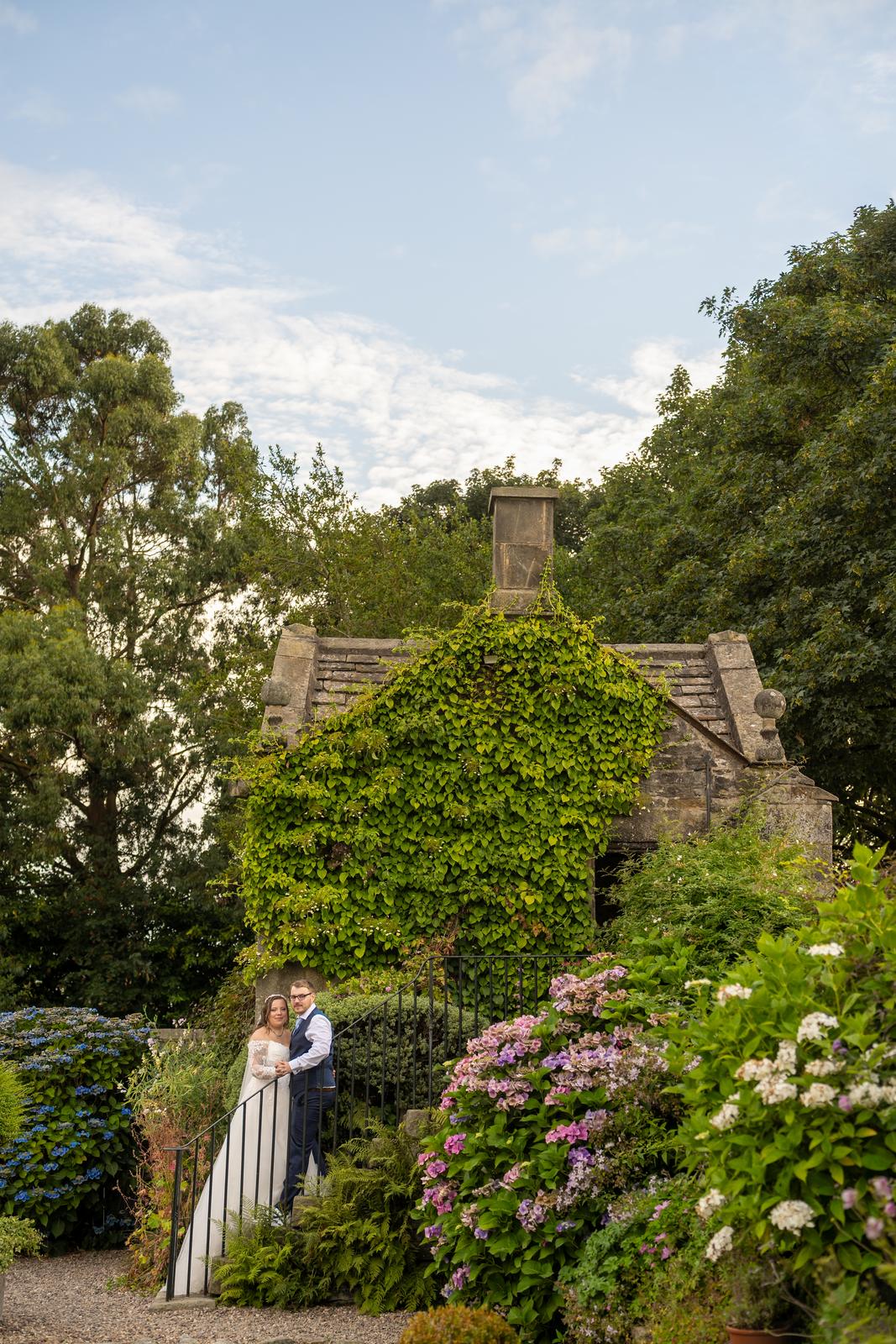 The newlyweds on the garden terrace beneath the ivy walls of Holdsworth House, West Yorkshire