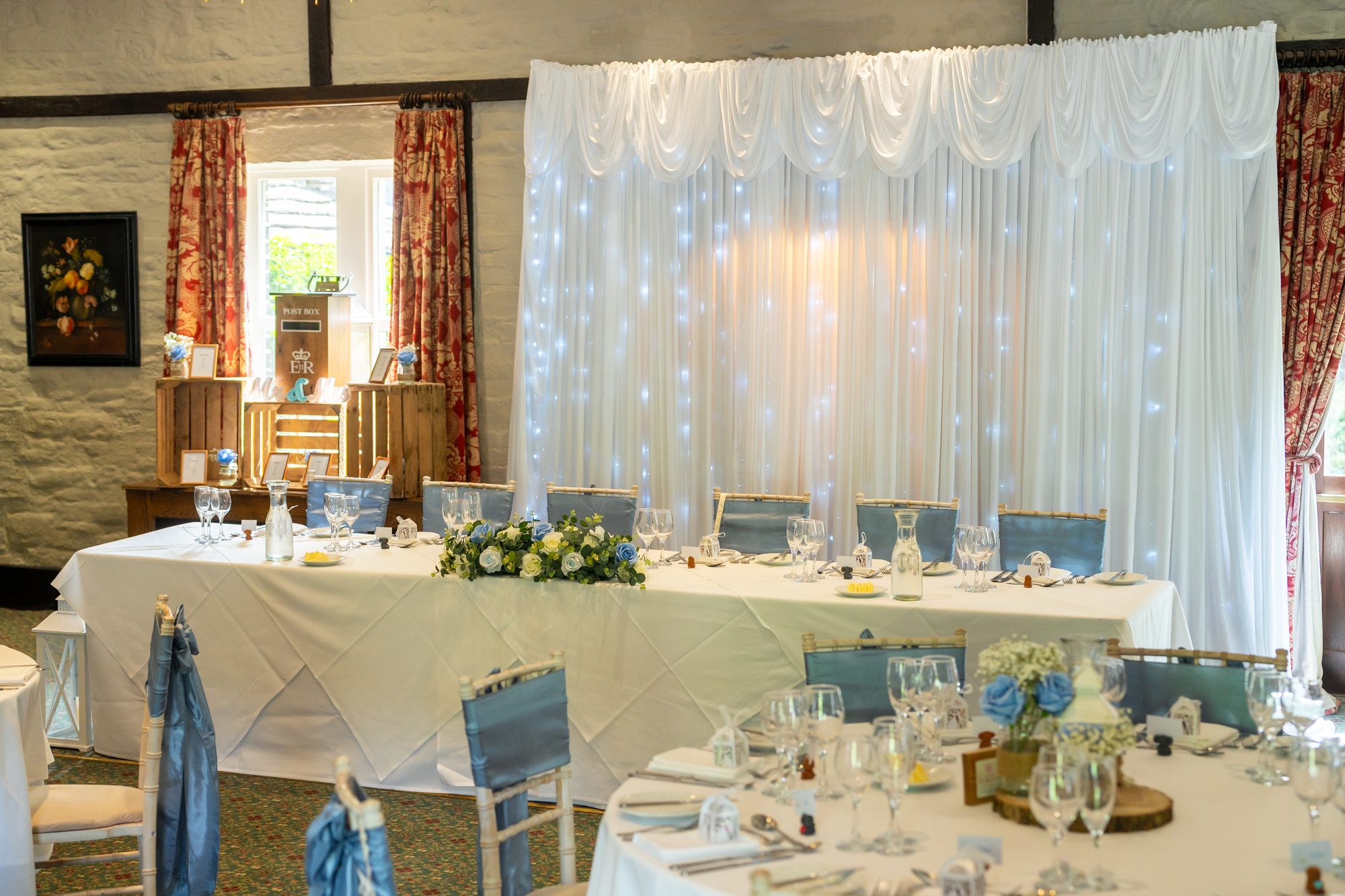 The wedding breakfast room at Holdsworth House with a fairy light curtain behind the top table
