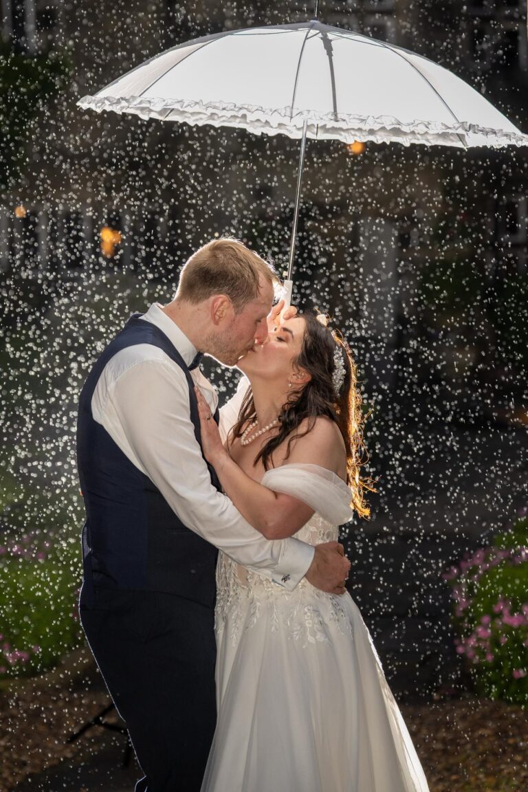 Ema and Tim kissing under a white umbrella in the rain at night