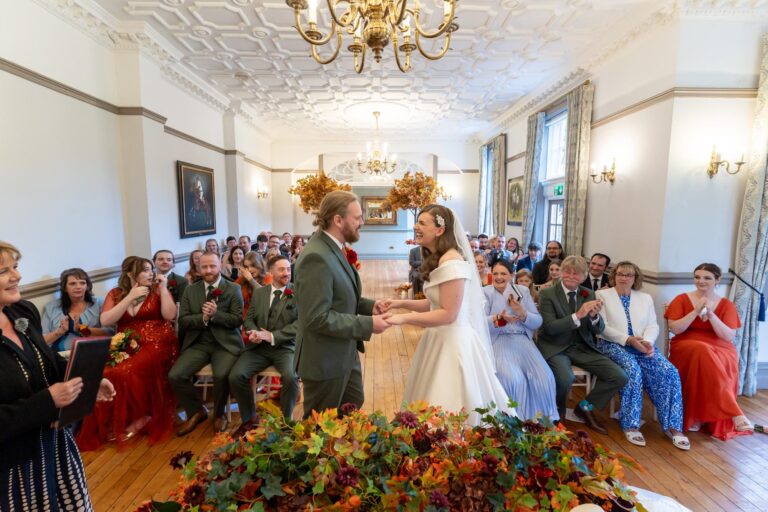 The ceremony room at Nunsmere Hall with chandeliers, guests and autumn leaves