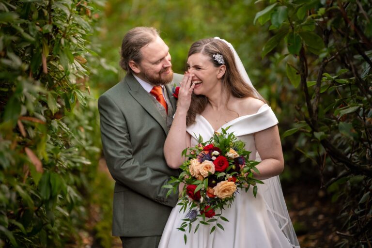 Naomi laughing with her autumn bouquet as David holds her close